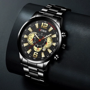 Macro shot of black stainless steel watch dial with gold markers and date display window