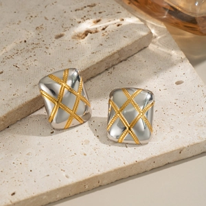 Close-up of square gold and silver earrings with classic quilted pattern on stone surface
