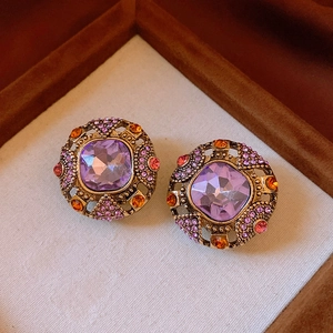 Vue macro de boucles d'oreilles vintage dorées avec cristal violet et strass colorés