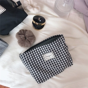 Detail view of the black and white gingham canvas makeup bag with a Time to Party fabric label
