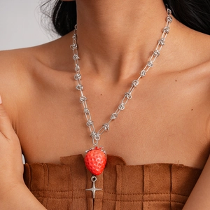 Detail of silver chain necklace featuring a realistic strawberry and star charm pendant