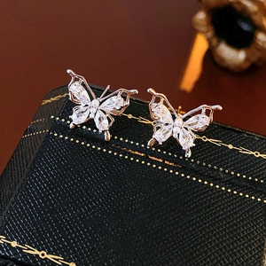 Macro detail of butterfly stud earrings with zircon wings and a white pearl accent