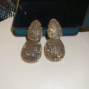 Macro shot of gold double teardrop earrings with luxury vintage pavé texture detail