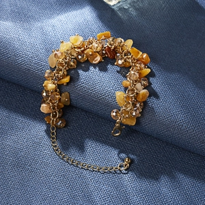 Detail of yellow raw crystal chips and amber beads on a gold-plated multi-link bracelet