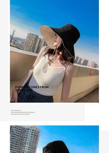 Fashionable black and beige sun hat with wide brim worn by model against city skyline