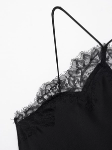 Détail de la bordure en dentelle noire et des fines bretelles sur une robe en satin