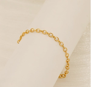 Detail of a golden O-chain bracelet on a white display with soft light and metallic shine