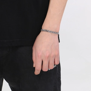 Gros plan d'un bracelet gourmette argenté porté par un homme au design de maillons minimalistes