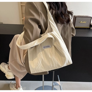 Detail der cremeweißen Schultertasche mit Strukturstoff und Kiss Yourself Etikett