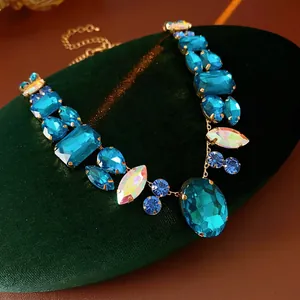 Luxurious gold necklace with blue and white multi-shape crystals on velvet box