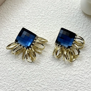 Macro view of blue crystal square earrings with gold metal ring fringe tassels