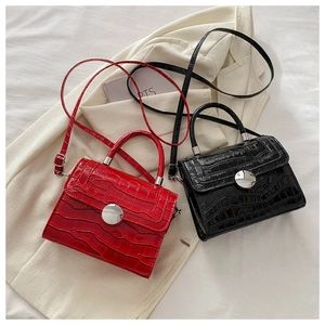 Detail of red and black crocodile embossed mini bags with silver circular metal clasps