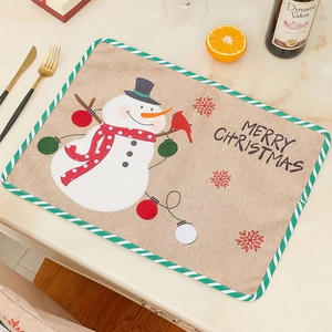 Linen Christmas placemat with embroidered snowman and red bird on marble tabletop
