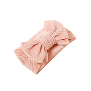 Pink corduroy baby headband with soft vertical ribbed texture and large decorative bow