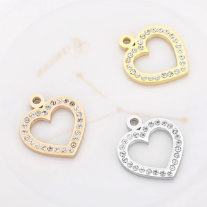Three heart-shaped rhinestone pendants in gold, rose gold, and silver on a white plate