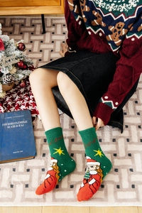 Close-up of green plush Christmas socks with Santa Claus pattern and warm festive details