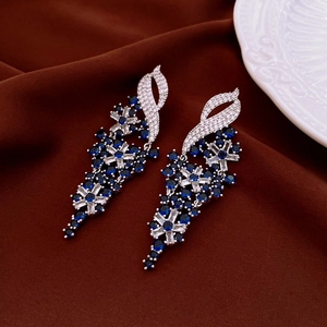 Macro view of silver butterfly tassel earrings with blue and white zircons on velvet