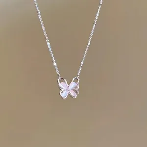 Macro detail of strawberry quartz butterfly pendant on a silver-tone link chain