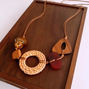 Detail of bohemian rattan necklace with wood and resin pendants on a wooden tray