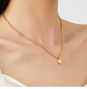 Gros plan d'un collier à perles plaqué or 18K avec pendentif ovale sur un modèle