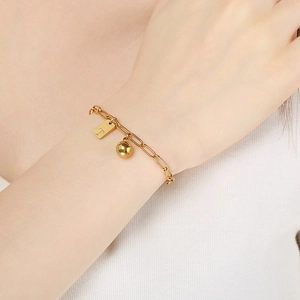 Bracelet chaîne dorée avec pendentif carré lettre T et perle, vue sur le poignet