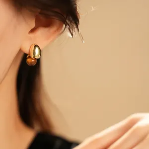 French vintage tiger eye stone earrings with polished gold metal beans on a female model