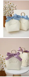 Detail of matte cream gift boxes with wooden ring handles and satin ribbon bows