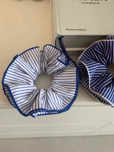 Close-up of oversized blue and white striped scrunchies with elegant wavy ruffled edges