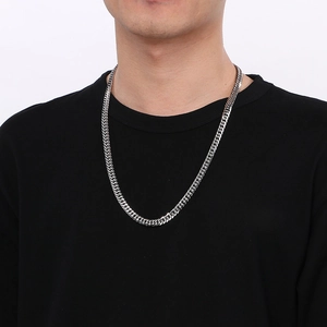 Close-up of a silver-toned bevel-cut curb chain necklace worn by a male model