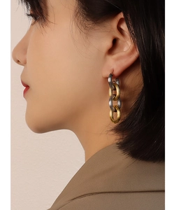Close-up of model wearing two-tone gold and silver chain link earrings in a luxury style