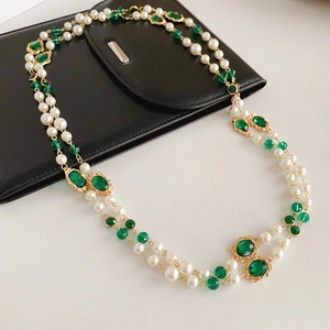 Detail of vintage multi-layer pearl necklace with green gemstones and gold chains