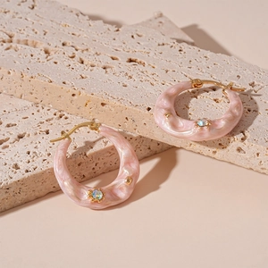 Detail of pink resin hoop earrings with gold metal accents and tiny zircon inlay