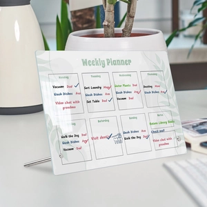 Acrylic weekly planner on a desk showing handwritten household tasks and metal stand