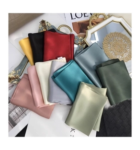 Close-up of stacked solid color mulberry silk scarves with elegant glossy satin texture