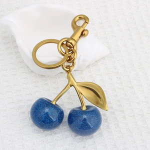 Makro-Detail von blauem Glitzer-Harz-Kirsch-Anhänger mit goldenem Blatt und Karabiner-Schlüsselring