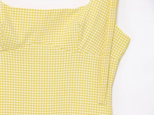 Detail of yellow and white gingham seersucker fabric with fine stitching on dress strap