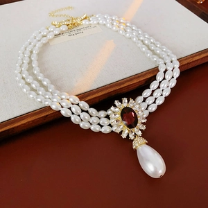 Macro detail of French vintage 3-strand pearl necklace with floral ruby pendant