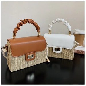 Detail of straw woven bags in brown and white with leather flip tops and pleated handles
