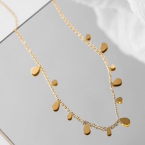 Close-up of golden double-layer snake chain with delicate water drop charms on mirror