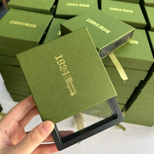 Detalle de una caja de regalo cuadrada verde para joyas con logotipo en pan de oro
