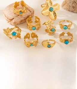Detail of gold floral rings in titanium steel with turquoise stones on stone texture