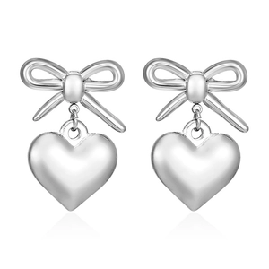 Polished silver bow and 3D heart earrings with elegant metallic luster on white background
