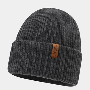 Close-up of chunky ribbed knit texture and brown leather label on dark grey beanie hat