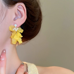Dettaglio degli orecchini a fiore giallo con perle e strass indossati dalla modella