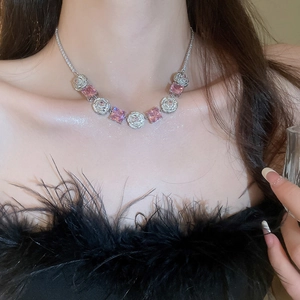 Close-up of elegant necklace with pink square gemstones and silver charms on model