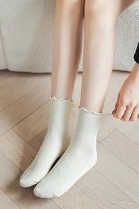 Detail of cream rib knit calf socks with ruffled edges and silk ribbon bow accent