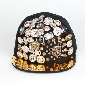 Dettaglio del cappello nero con testa di leopardo dorata, borchie e bottoni vintage
