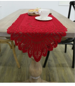 Detailed close-up of red lace Christmas table runner with intricate hollow knit pattern