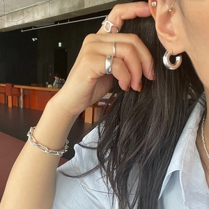 Close-up of minimalist 925 sterling silver hoop earrings, rings and chain bracelet on model