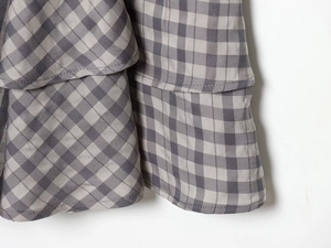 Detailed view of layered plaid ruffles with clean stitched edges on a cotton dress